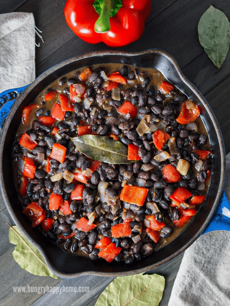 A blue enameled cast iron pan with the Caribbean black beans in it.  A green bay leaf is on top.