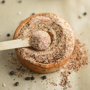 homemade steak seasoning: chili steak rub in a small clay bowl with a wooden spoon