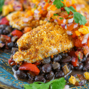main image of baked crusted tilapia on top of black beans topped with fresh orange salsa