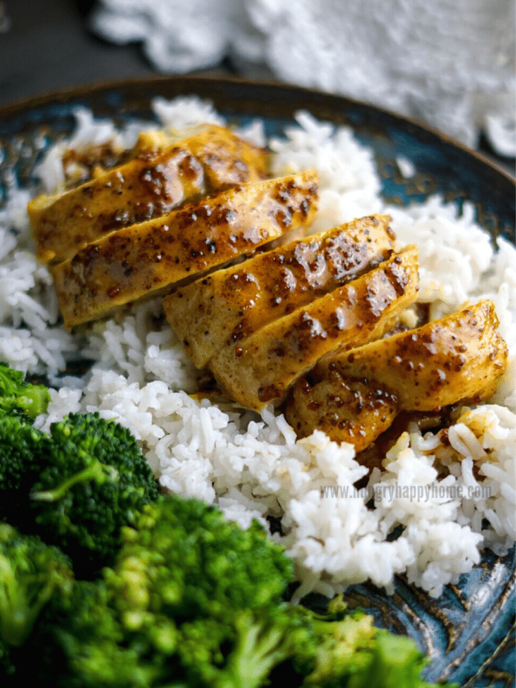 Curry Maple Mustard Chicken on a blue ceramic plate with rice and steamed broccoli.