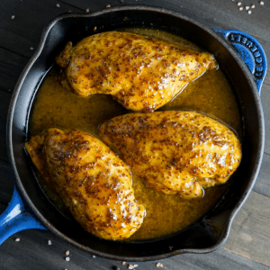 Curry maple mustard chicken in a cast iron pan.