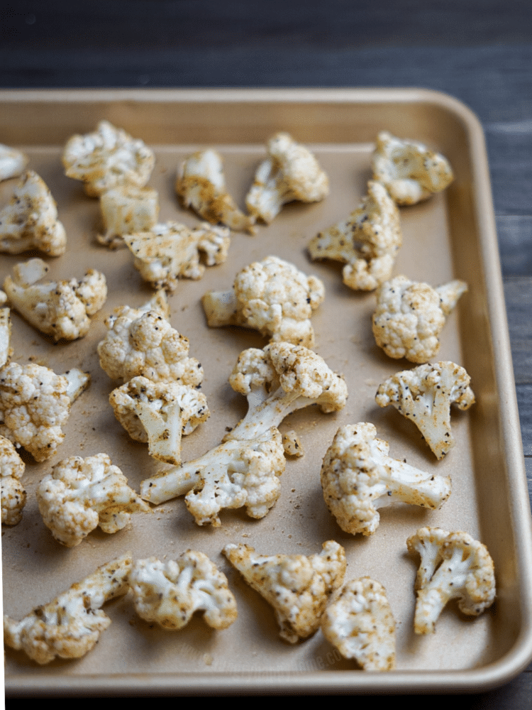 Seasoned and uncooked cumin cauliflower on a baking sheet.