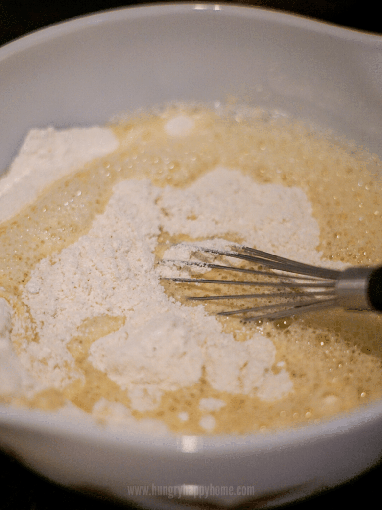 A white bowl with cornbread batter being whisked.