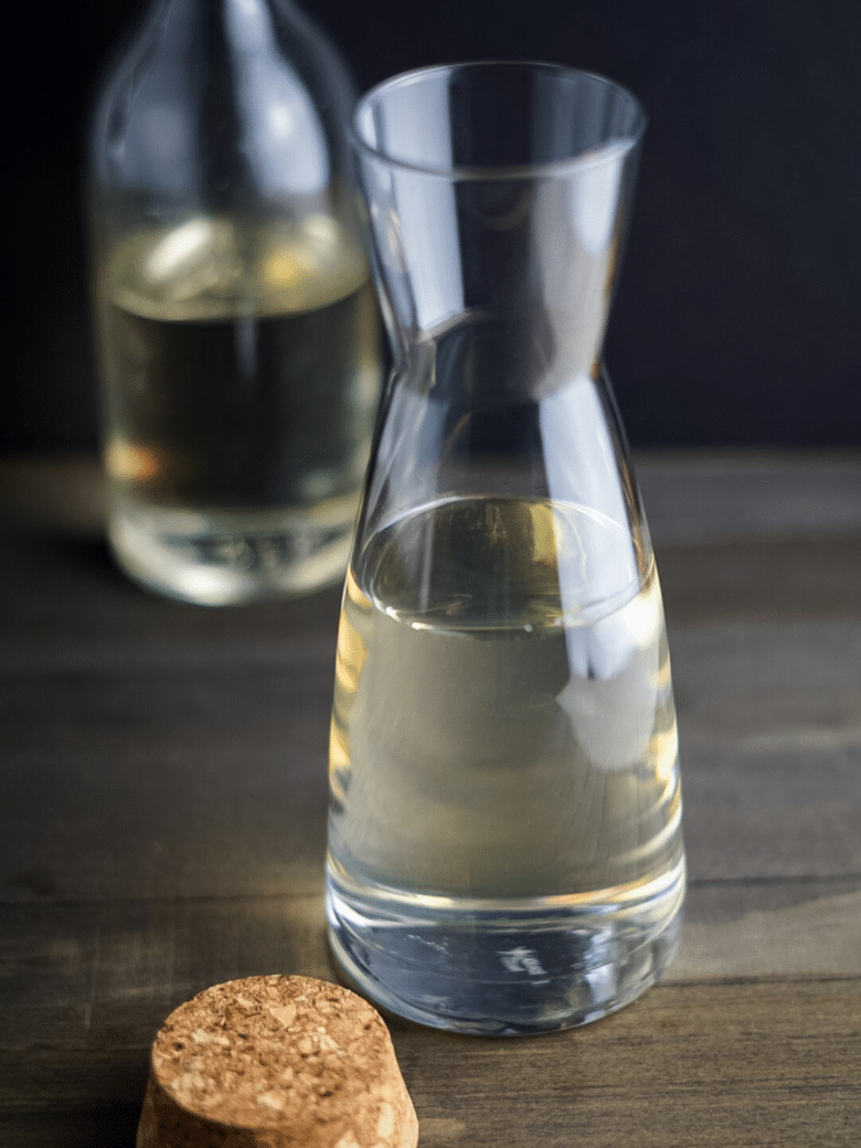 Homemade Simple Syrup in a clear glass bottle. A cork lid to the bottle is next to it.