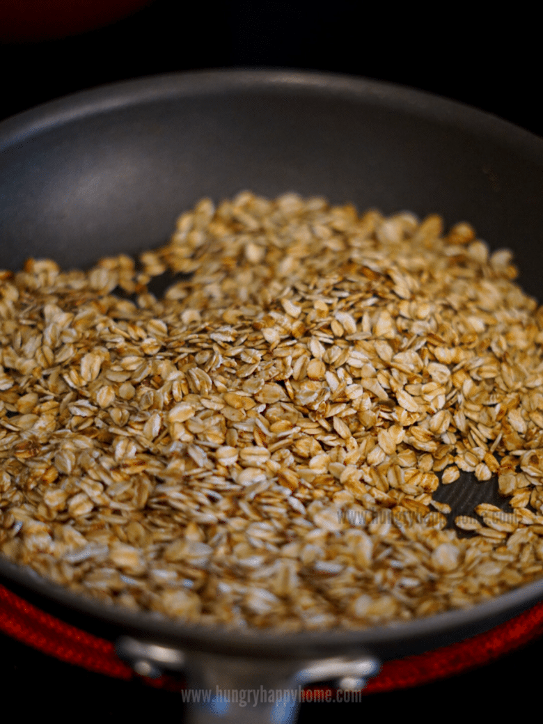 Toasted rolled oats in a pan on the stove.
