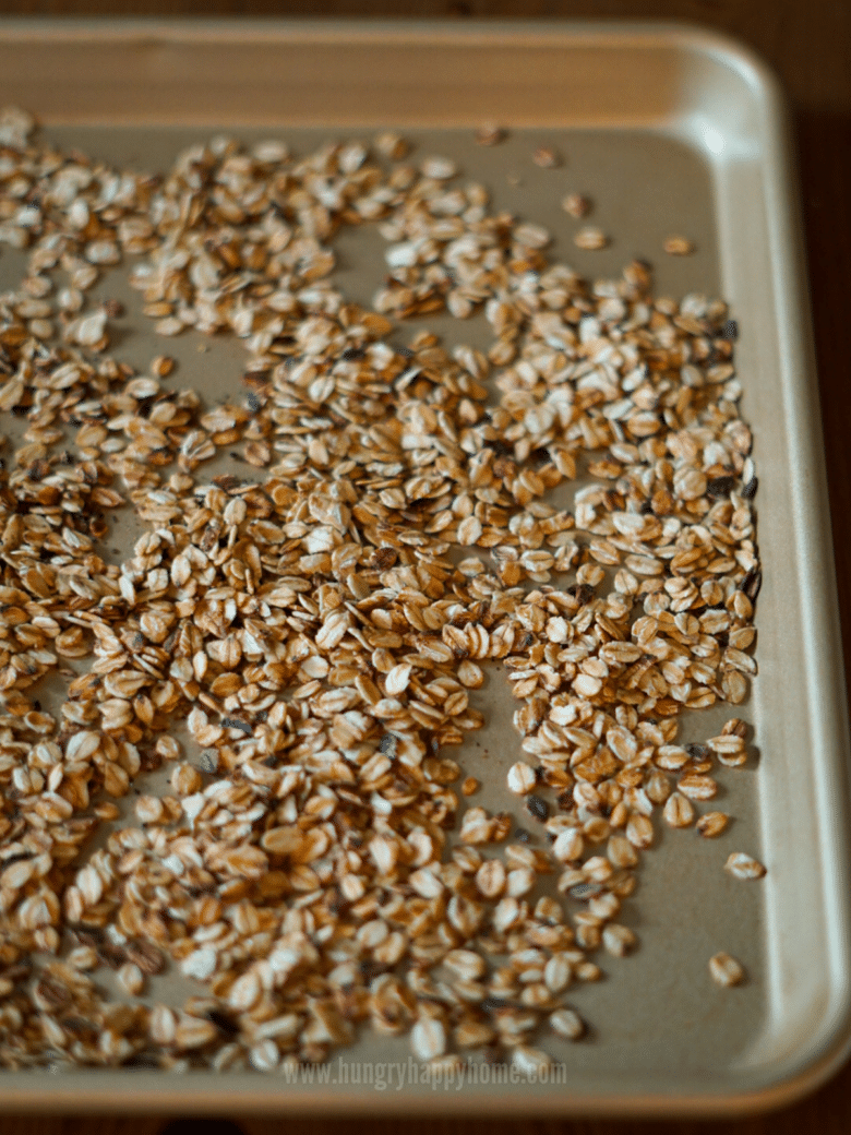 Toasted rolled oats spread out on a large baking dish to cool.