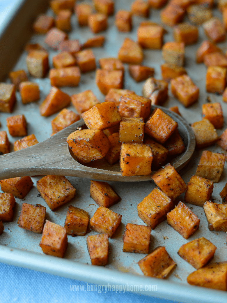 Roasted cinnamon chipotle sweet potatoes on baking dish with a wooden spoon.