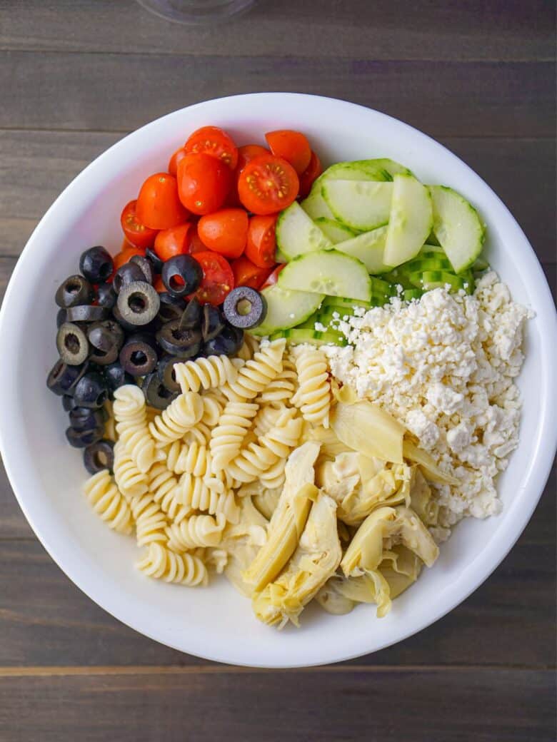 White bowl containing the ingredients to make Quick and Easy Pasta Salad.