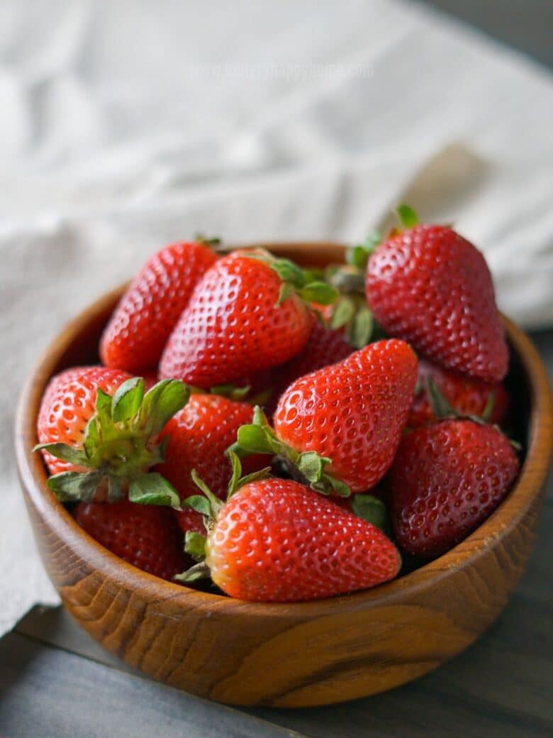 Wooden bowl filled with fresh strawberries.