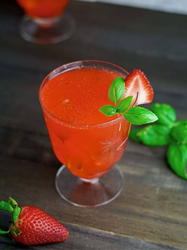 Basil Strawberry Lemonade in an antique glass with strawberry and basil garnish.